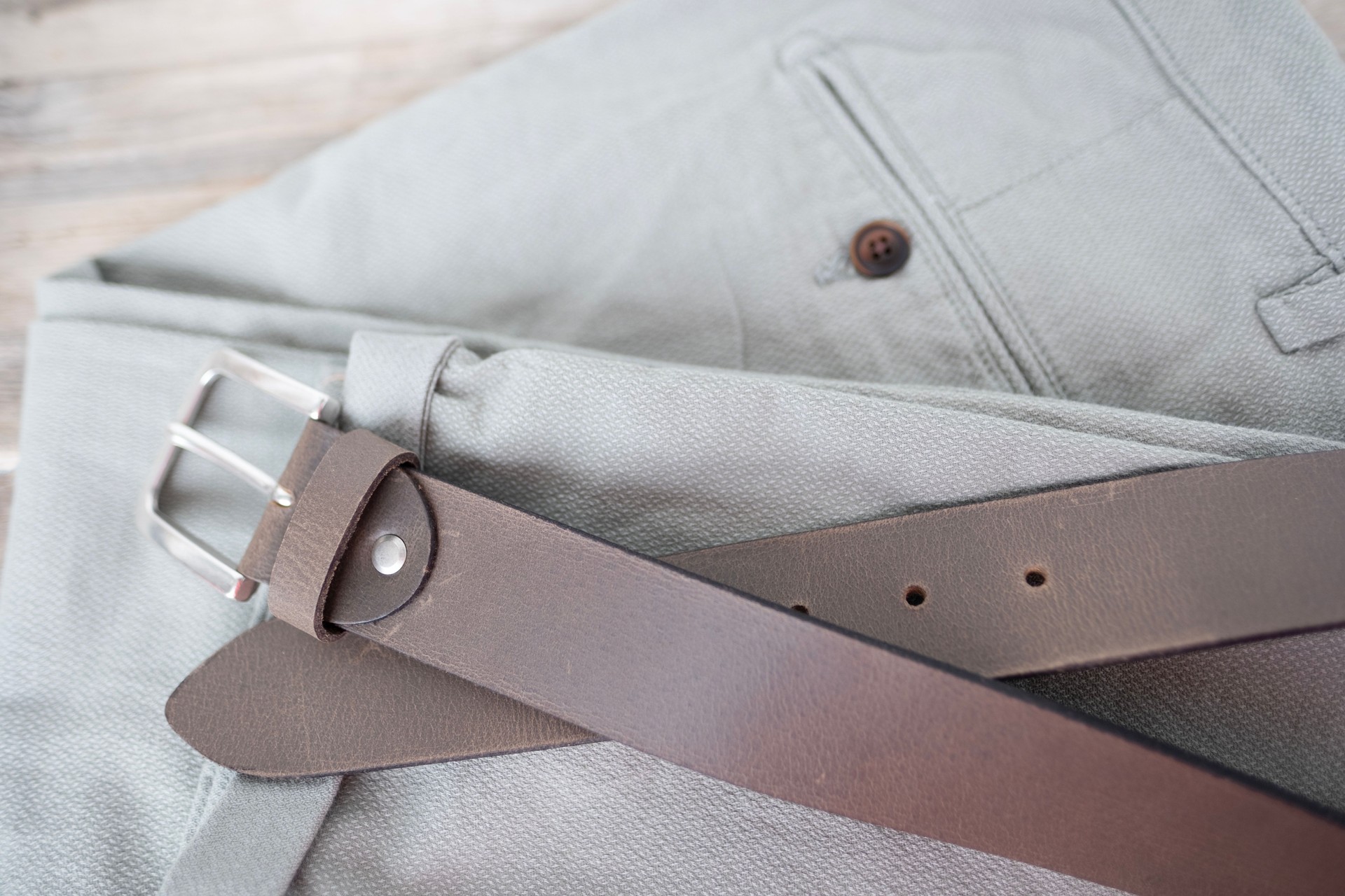Brown classic leather belt with silver buckle on light gray pants, Classic men's accessory. Fashion and style, must-have accessory for modern man