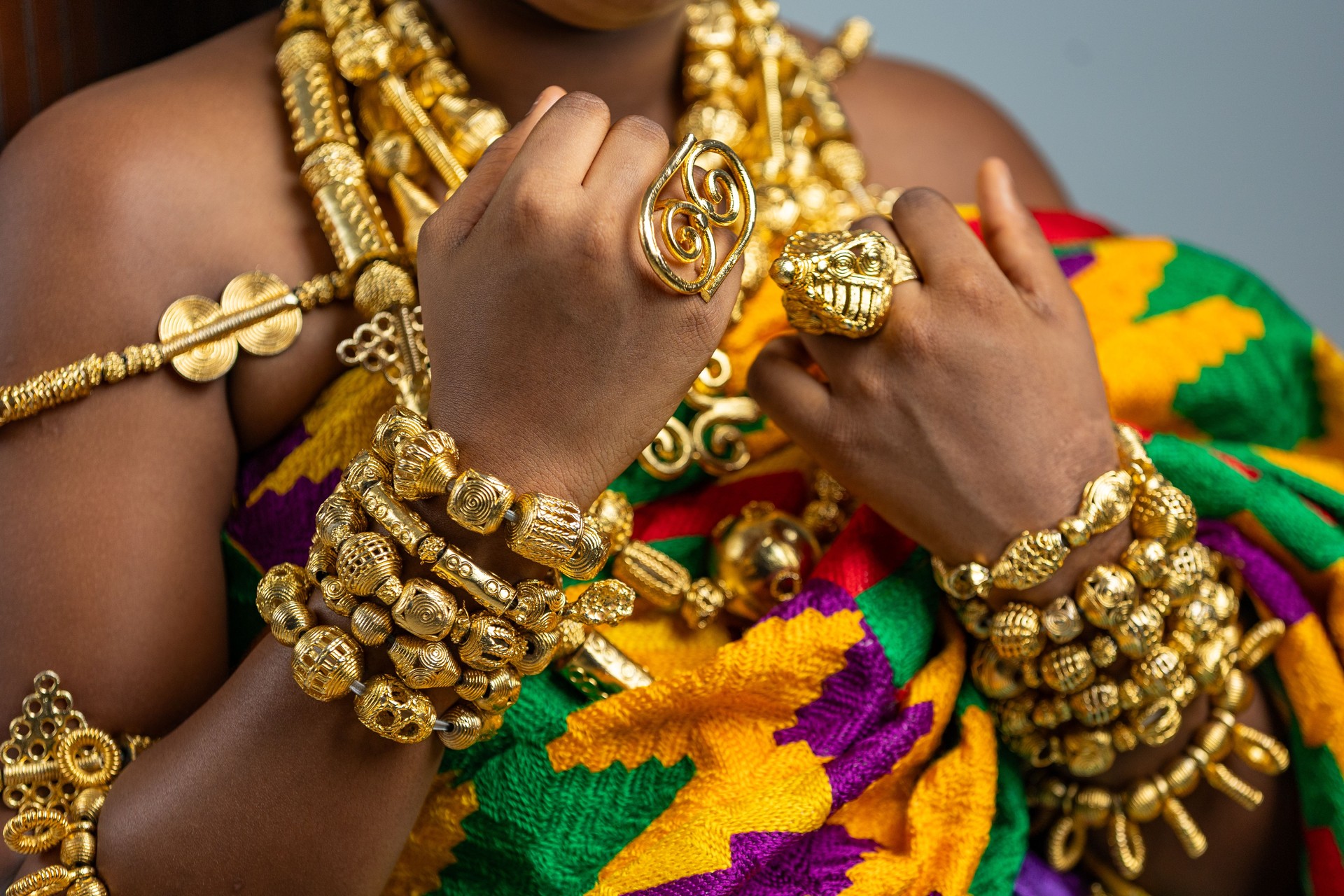 Rich Ghanaian royalty regalia. Traditional African culture and heritage, gold ring jewellery, necklace and bracelet ornaments worn on Kente cloth.