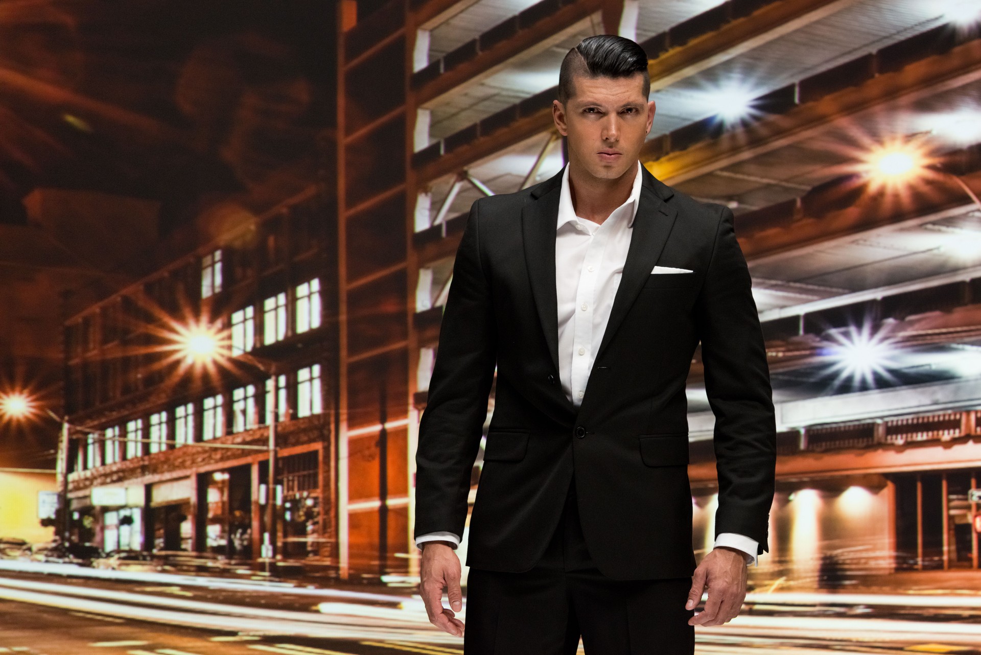 One man only / waist up / front view / looking at camera of 30-39 years old adult handsome people / short hair latin american and hispanic ethnicity male / young men business person / businessman standing / blurred motion in front of black background