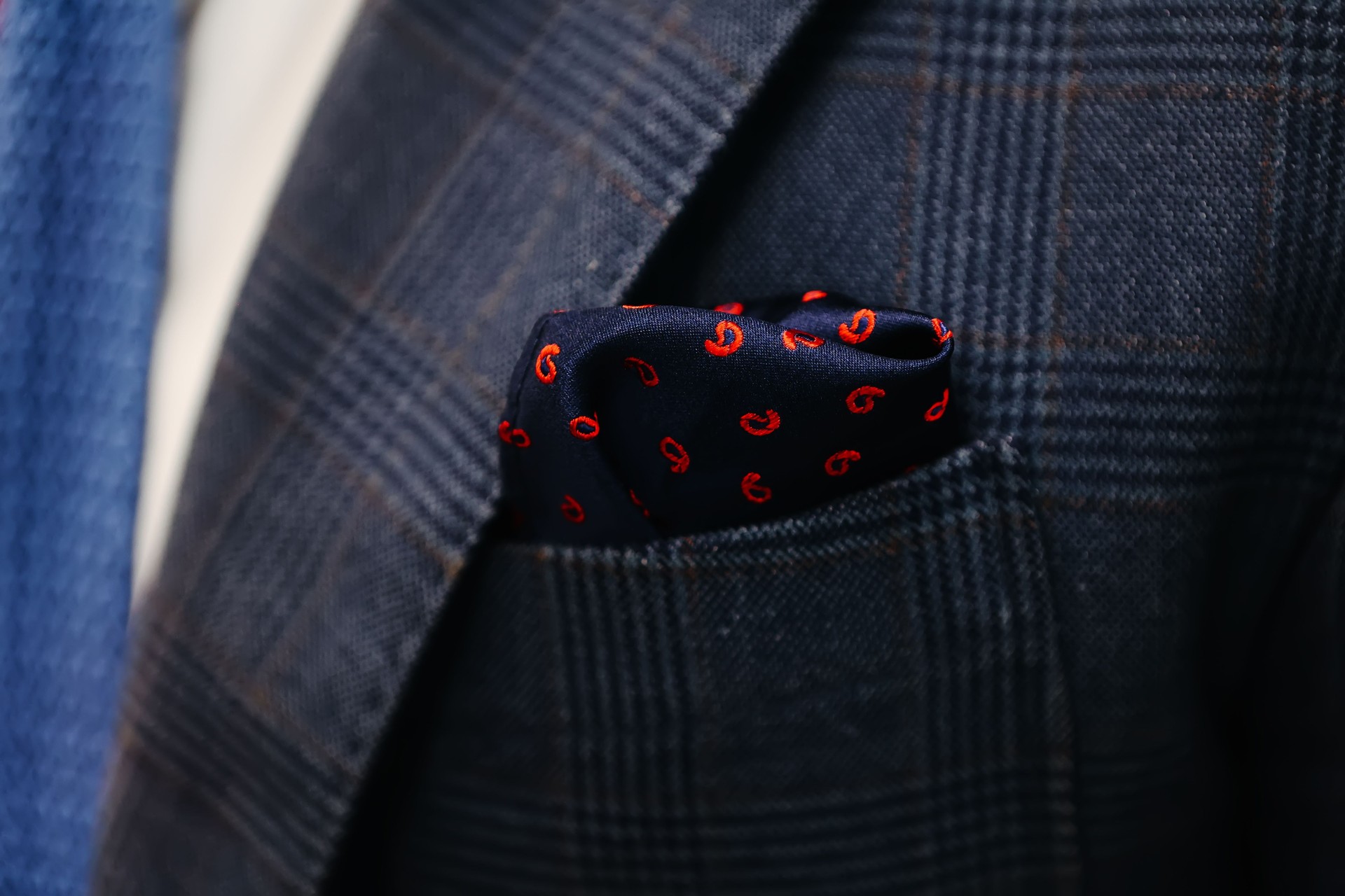 Navy blue pocket square elegantly tucked into the pocket of a plaid suit jacket