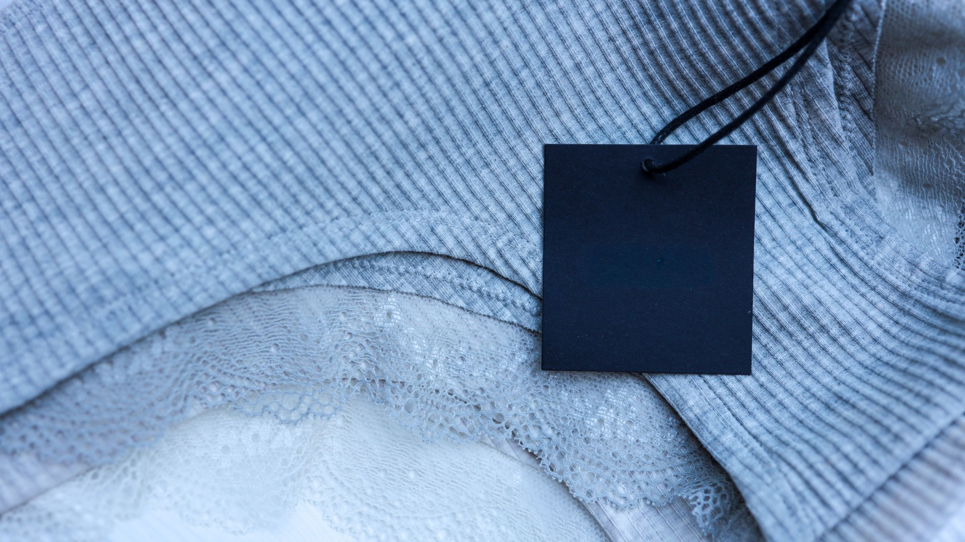 Close-up of a gray ribbed fabric with a black tag and lace detail.